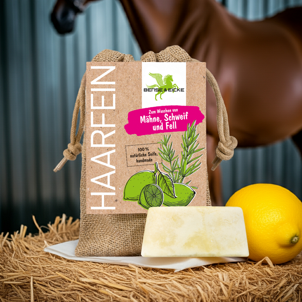 Bense & Eicke HaarFein Seife für Mähne, Schweif und Fell im Jutesack den man auch zum Einschäumen und Waschen benutzen kann auf einem Strohballen mit einer Zitrone und im Hintergrund ein Pferd vor hellblauem Wellblech 