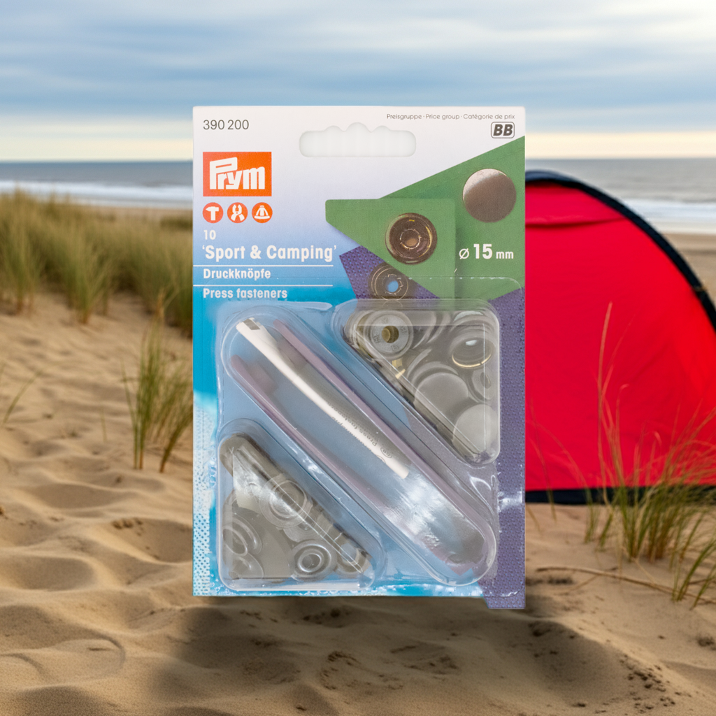 CasaBellissimo Prym Druckknöpfe "Sport & Camping", nähfrei, Ø 15 mm, brüniert und mit Werkzeug in der Blister Verpackung im Hintergrund ein rotes Zelt in den Dünen am Strand