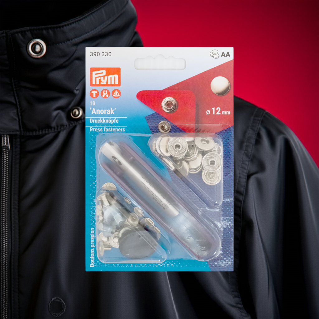 Prym Druckknöpfe "Anorak", nähfrei, Ø 12 mm  silberfarbig und mit Werkzeug in der Blister Verpackung dunkelroter Hintergrund mit einem schwarzen Anorak