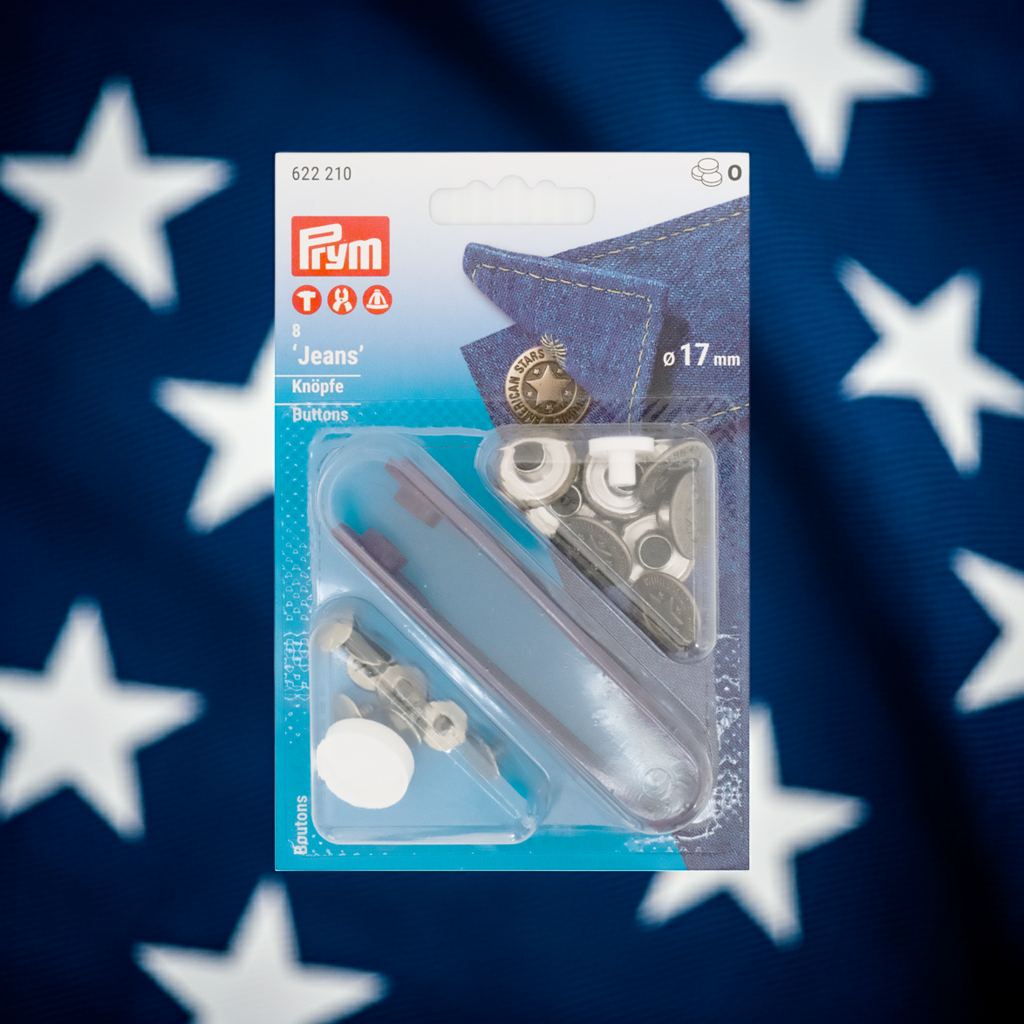 Prym Jeansknöpfe "American Star", nähfrei, Ø 17 mm in altsilber und mit Werkzeug in der Blister Verpackung im Hintergrund weiße Sterne auf dunkelblauem Grund