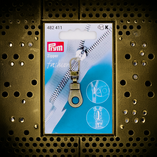 CasaBellissimo Prym Reißverschluß Zipper Fashion Anhänger "Öse"  in altmessing auf altmessingfarbenem Lochblech Hintergrund